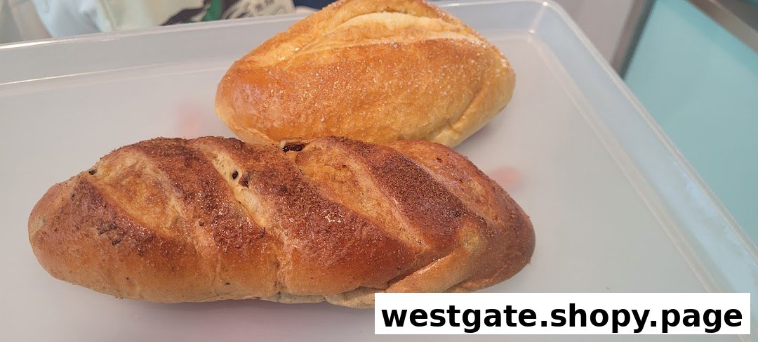 Two freshly baked loaves of bread, one plain and one with raisins, on a white tray.