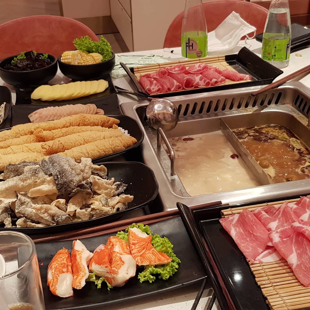 A vibrant hotpot spread featuring various fresh ingredients and two simmering broths.