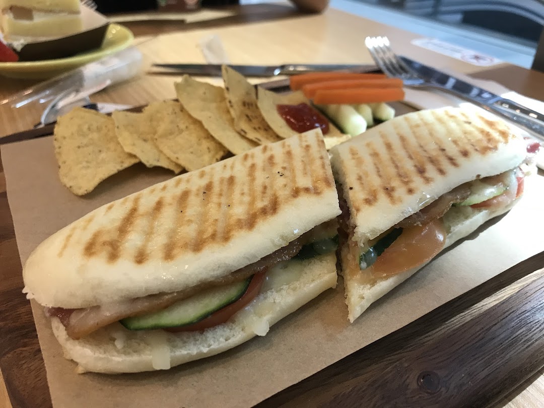 A delicious grilled panini served with tortilla chips and fresh vegetables on a wooden board.
