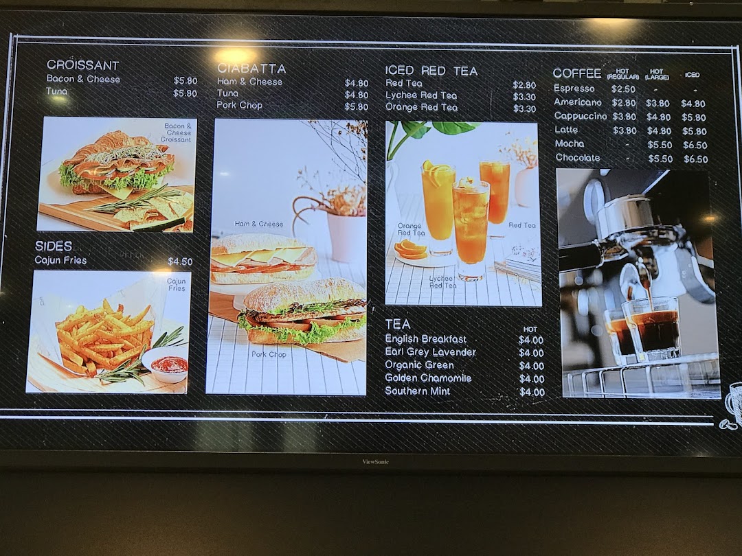 A digital menu board displaying various croissants, ciabattas, sides, coffees, and teas with prices.