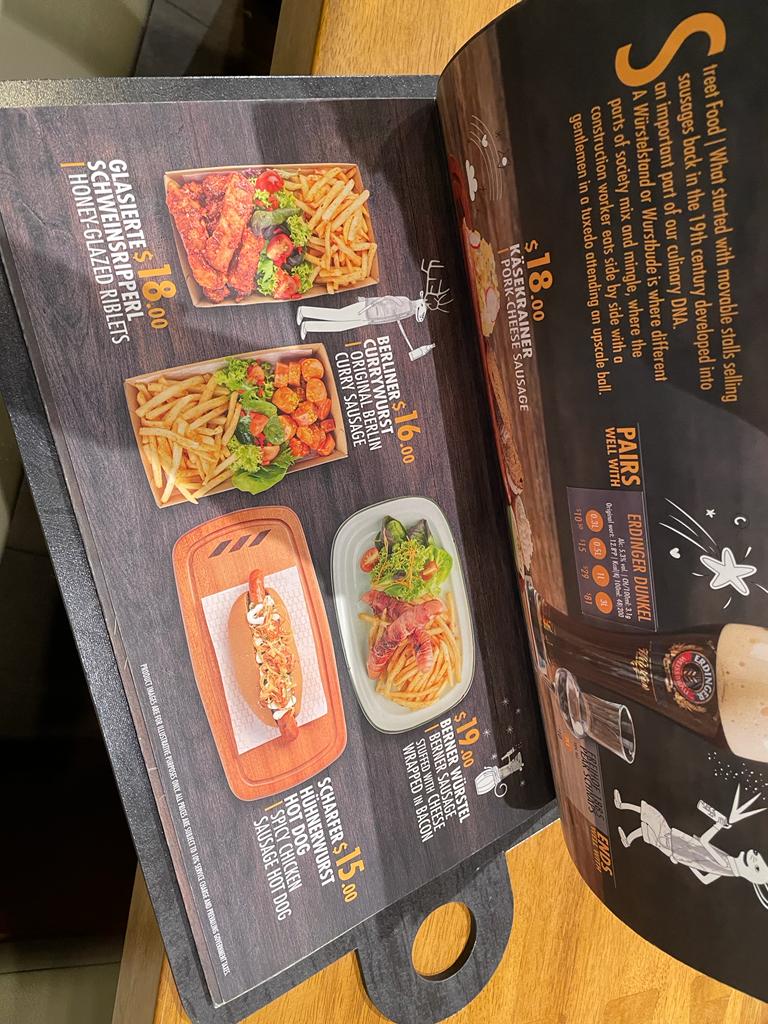 A page from a German restaurant menu showcasing various street food items and beer pairings.