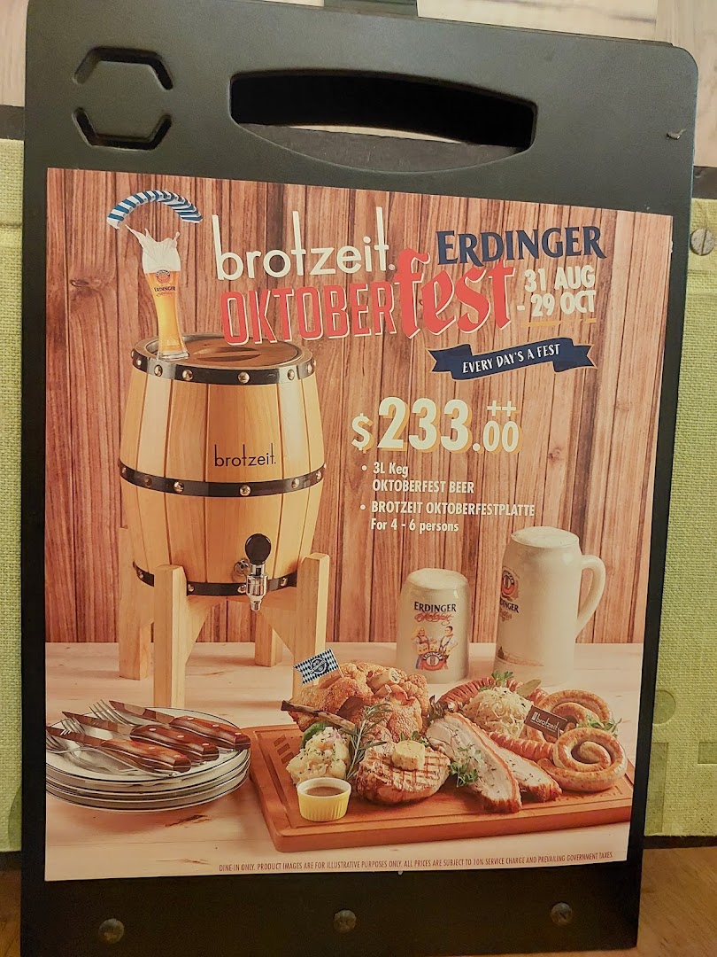 A promotional stand for Brotzeit's Oktoberfest special, featuring a beer keg and a large food platter.