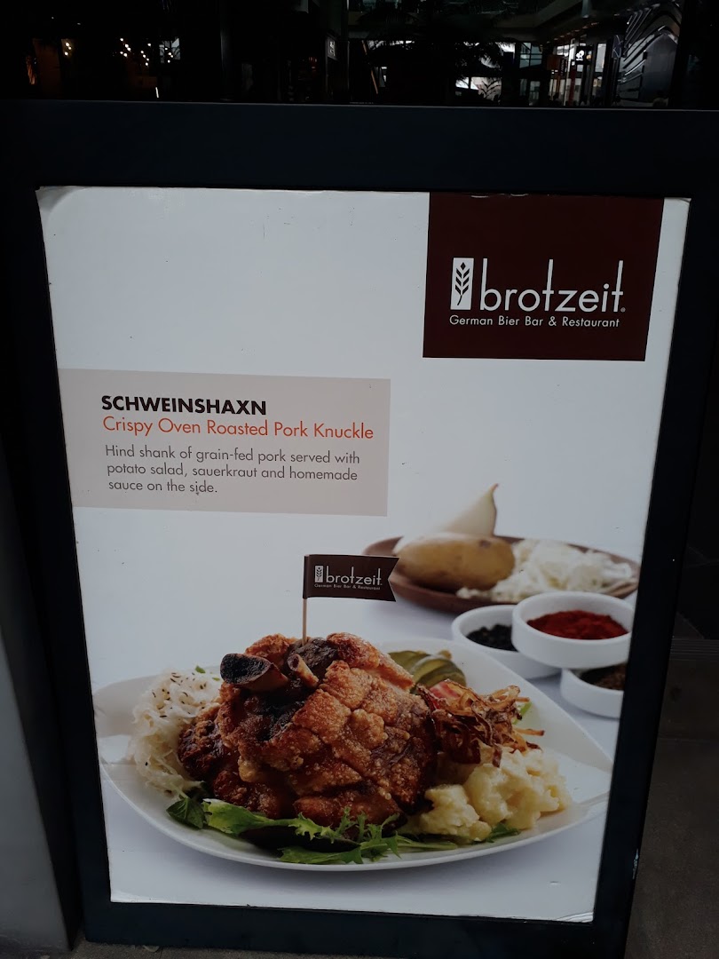 A promotional display board featuring Brotzeit's Crispy Oven Roasted Pork Knuckle (Schweinshaxn) with description.