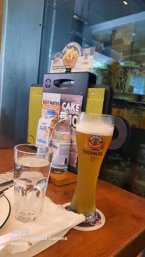 A glass of Erdinger beer, water, and promotional displays on a wooden table at Brotzeit.