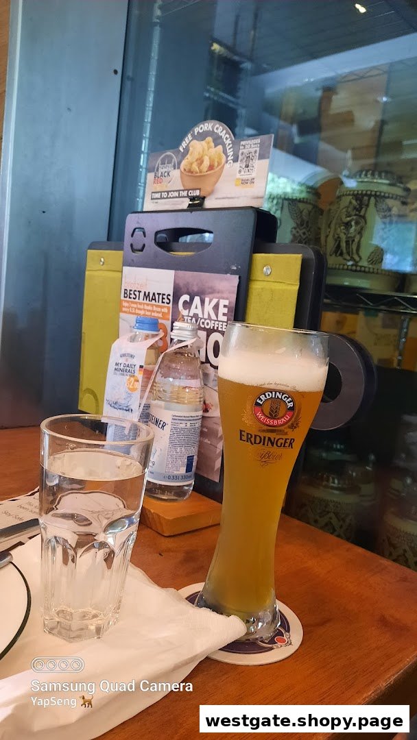 A glass of Erdinger beer, water, and promotional displays on a wooden table at Brotzeit.