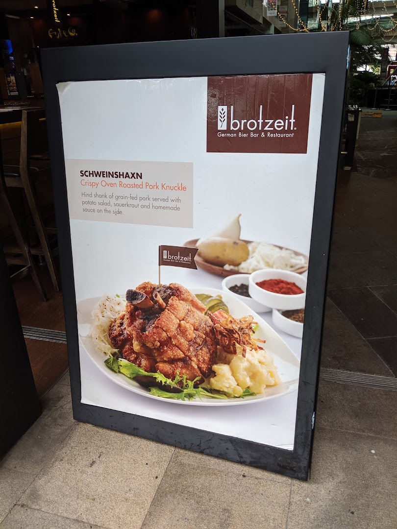 A display board showcasing Brotzeit's signature Crispy Oven Roasted Pork Knuckle (Schweinshaxn).