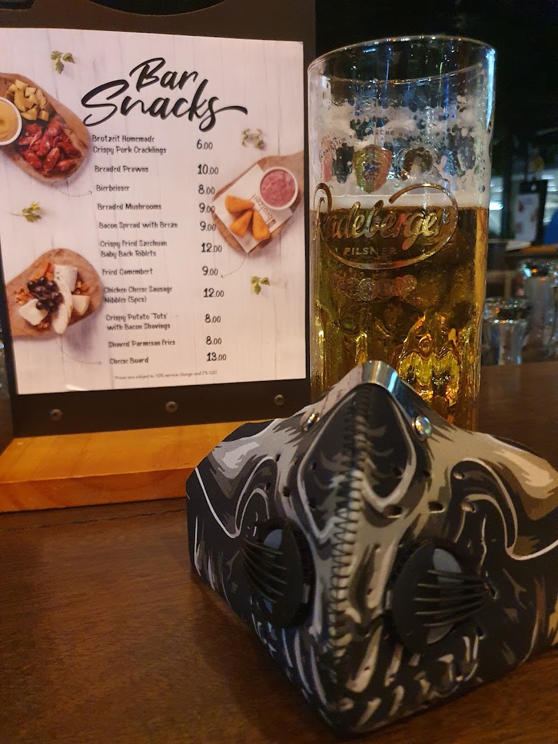 A menu stand displaying 'Bar Snacks' with prices, next to a glass of beer and a face mask.
