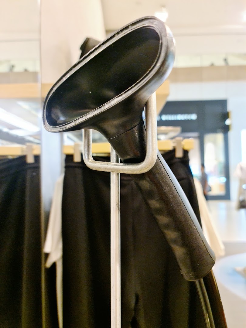 A close-up of a garment steamer in a Calvin Klein store, with clothing racks in the background.