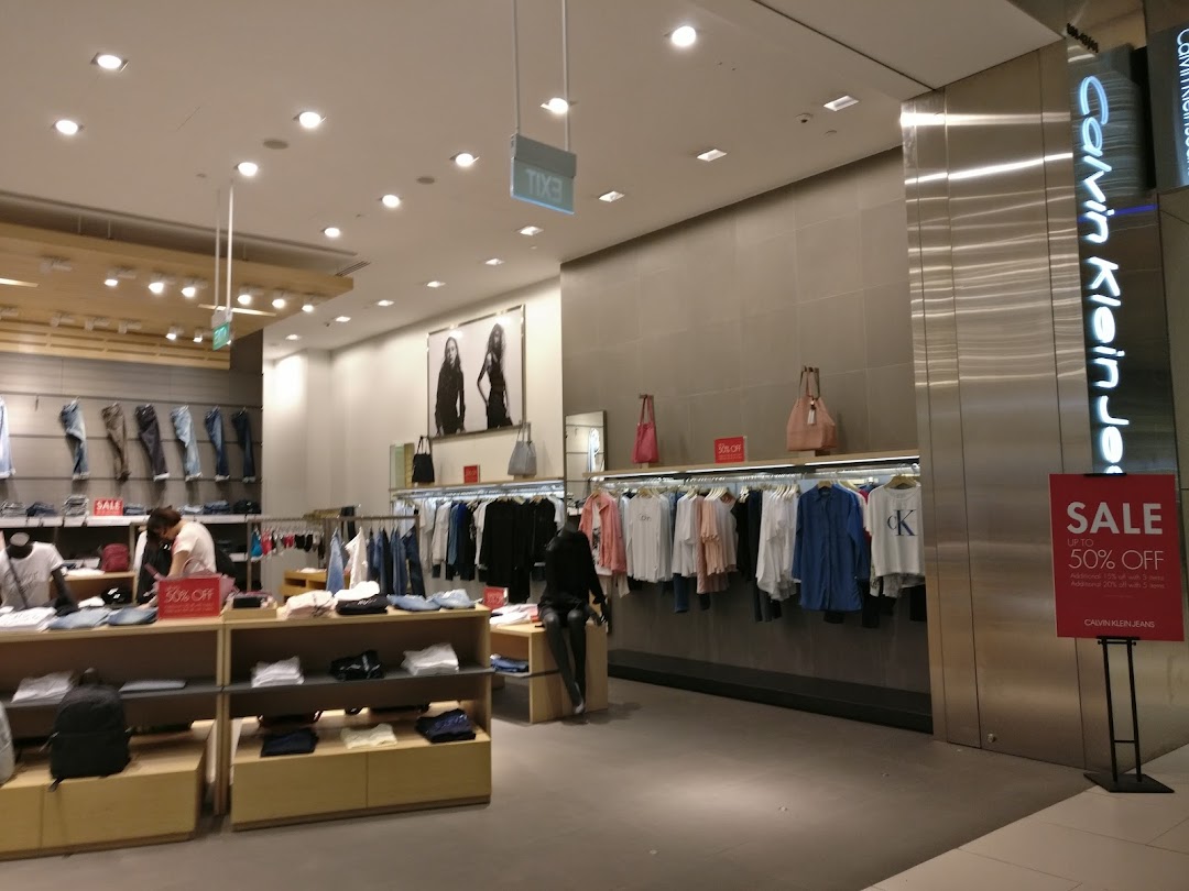 Interior view of a Calvin Klein store showcasing clothing displays and a prominent sale sign.