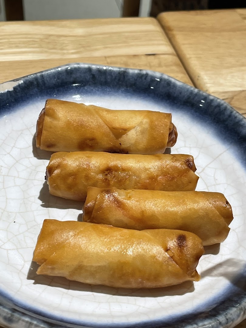 A plate of four golden-brown spring rolls, showcasing a delicious appetizer.