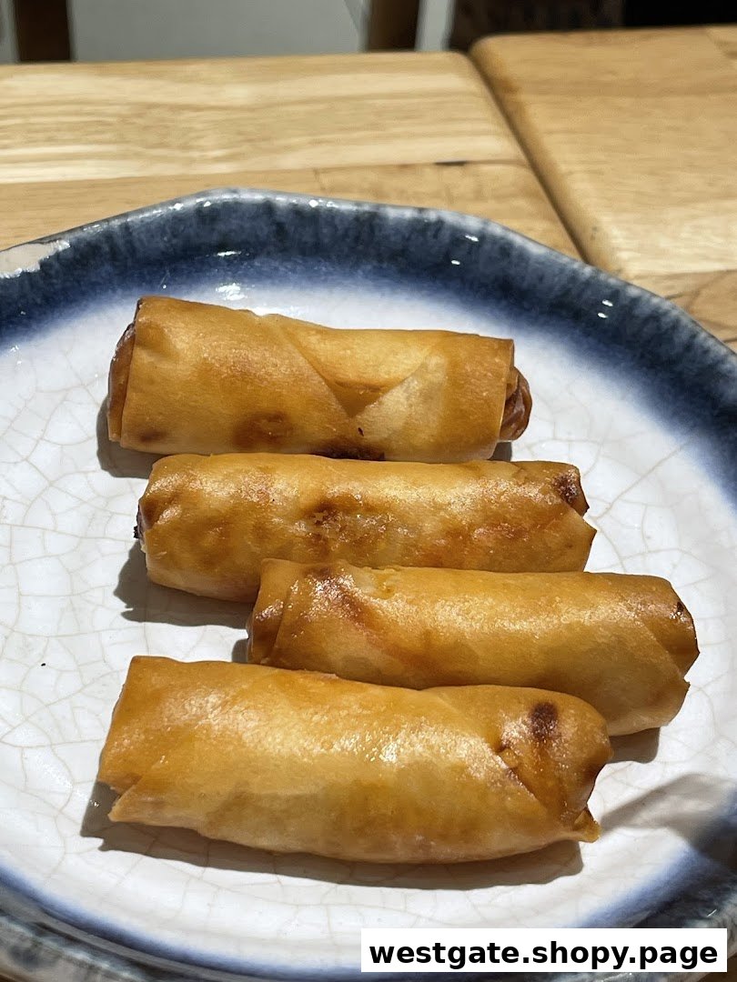 A plate of four golden-brown spring rolls, showcasing a delicious appetizer.