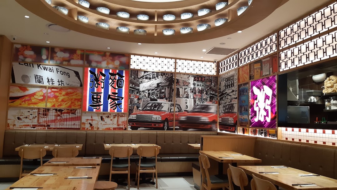 Interior view of Canton Paradise Noodle Congee House featuring Hong Kong-themed wall art and wooden dining tables.