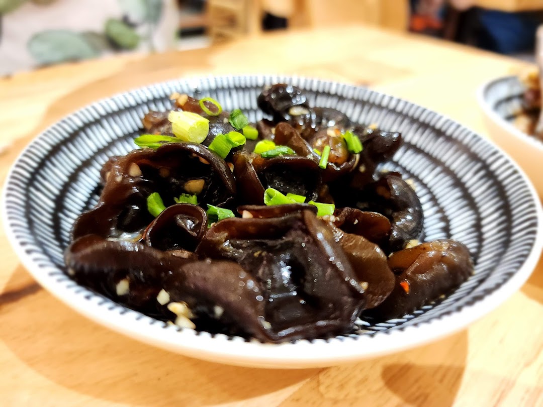A close-up of a bowl of seasoned black fungus (wood ear mushrooms) garnished with green onions.