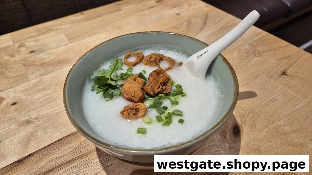A comforting bowl of congee topped with fried dough, spring onions, and cilantro on a wooden table.