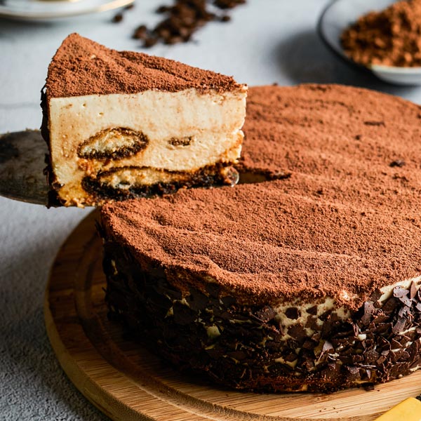 A delicious slice of tiramisu-style cake being served from a whole cake.