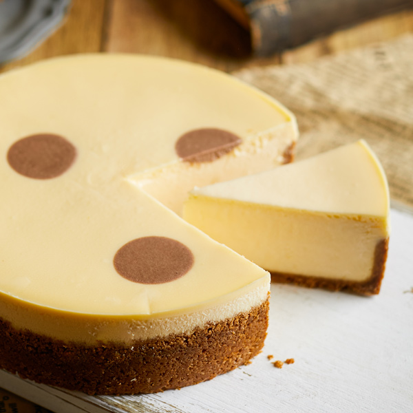 A creamy cheesecake with a slice removed, showcasing its rich texture and crumbly base.