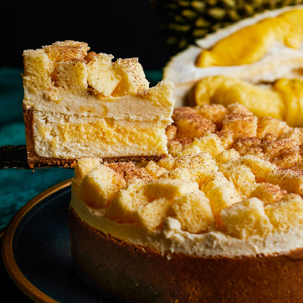 A delicious slice of multi-layered durian cake being served from a whole cake.