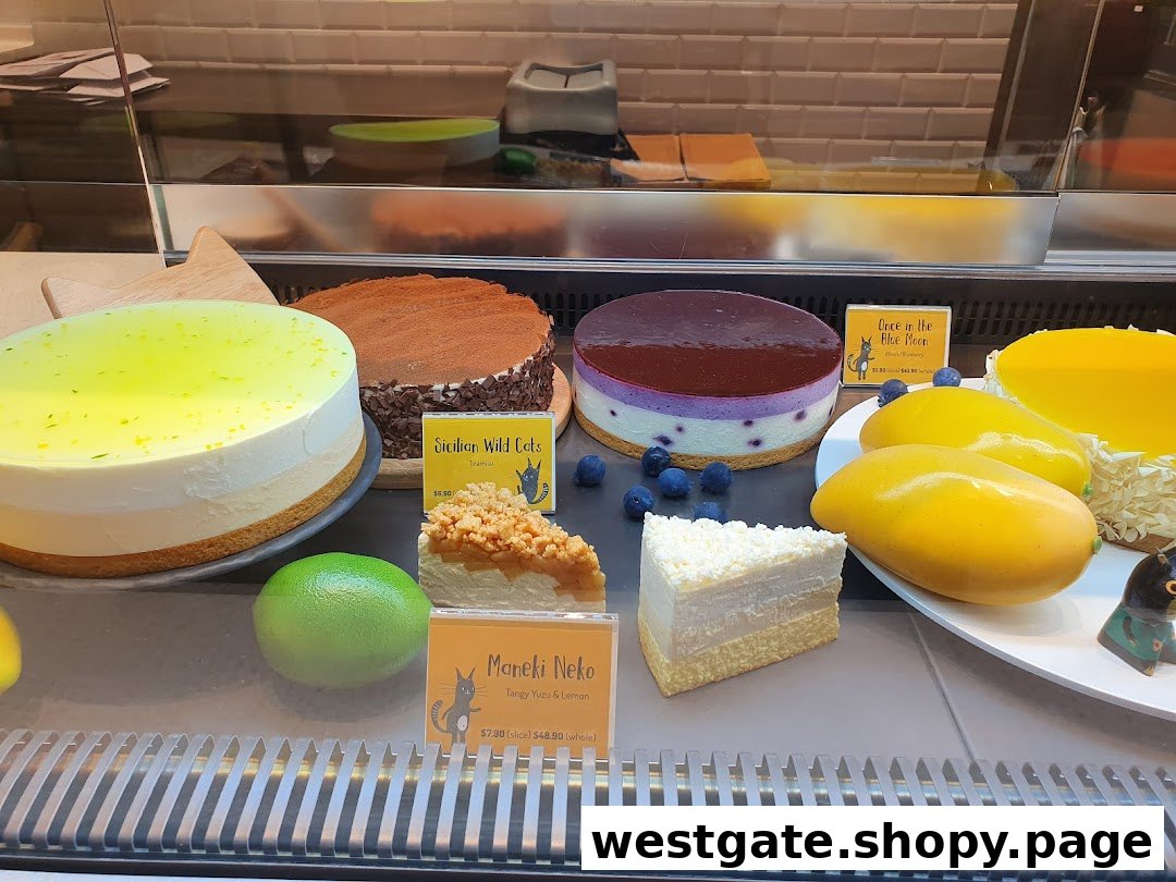 A vibrant display of delicious cakes and desserts in a brightly lit showcase.