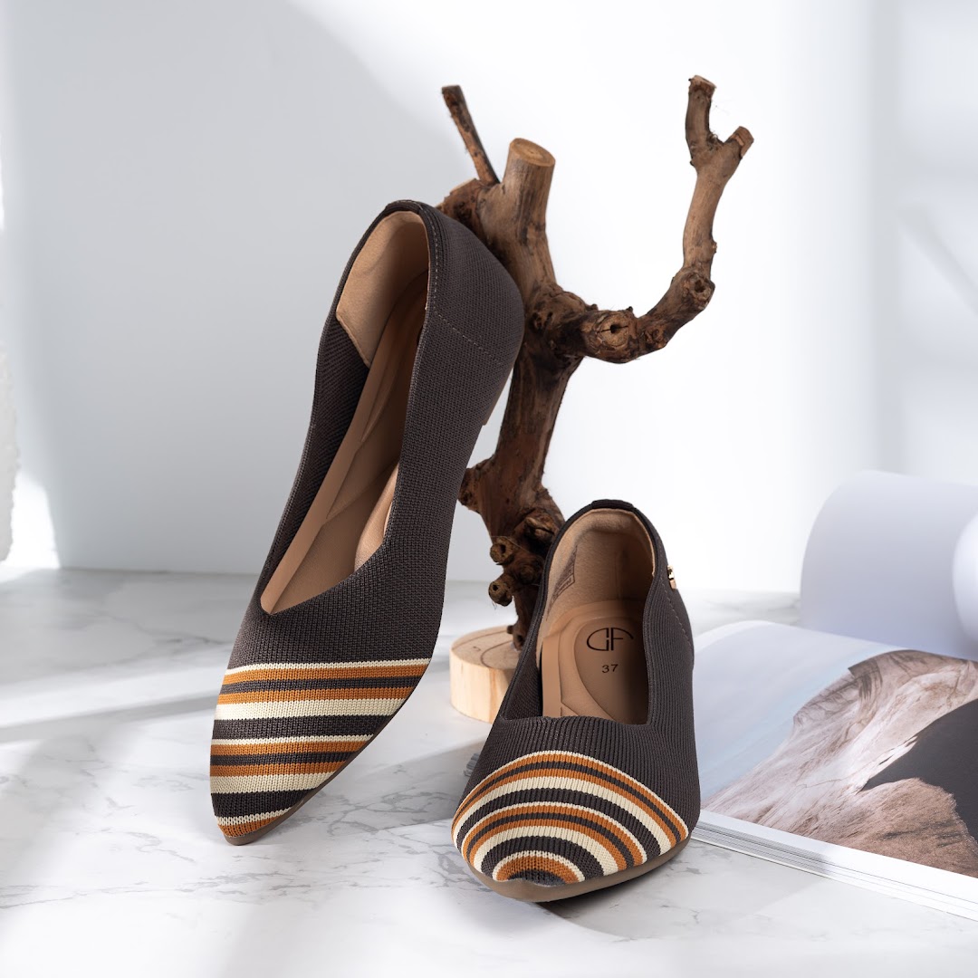 A pair of stylish dark grey knitted flats with striped toes displayed on a marble surface.