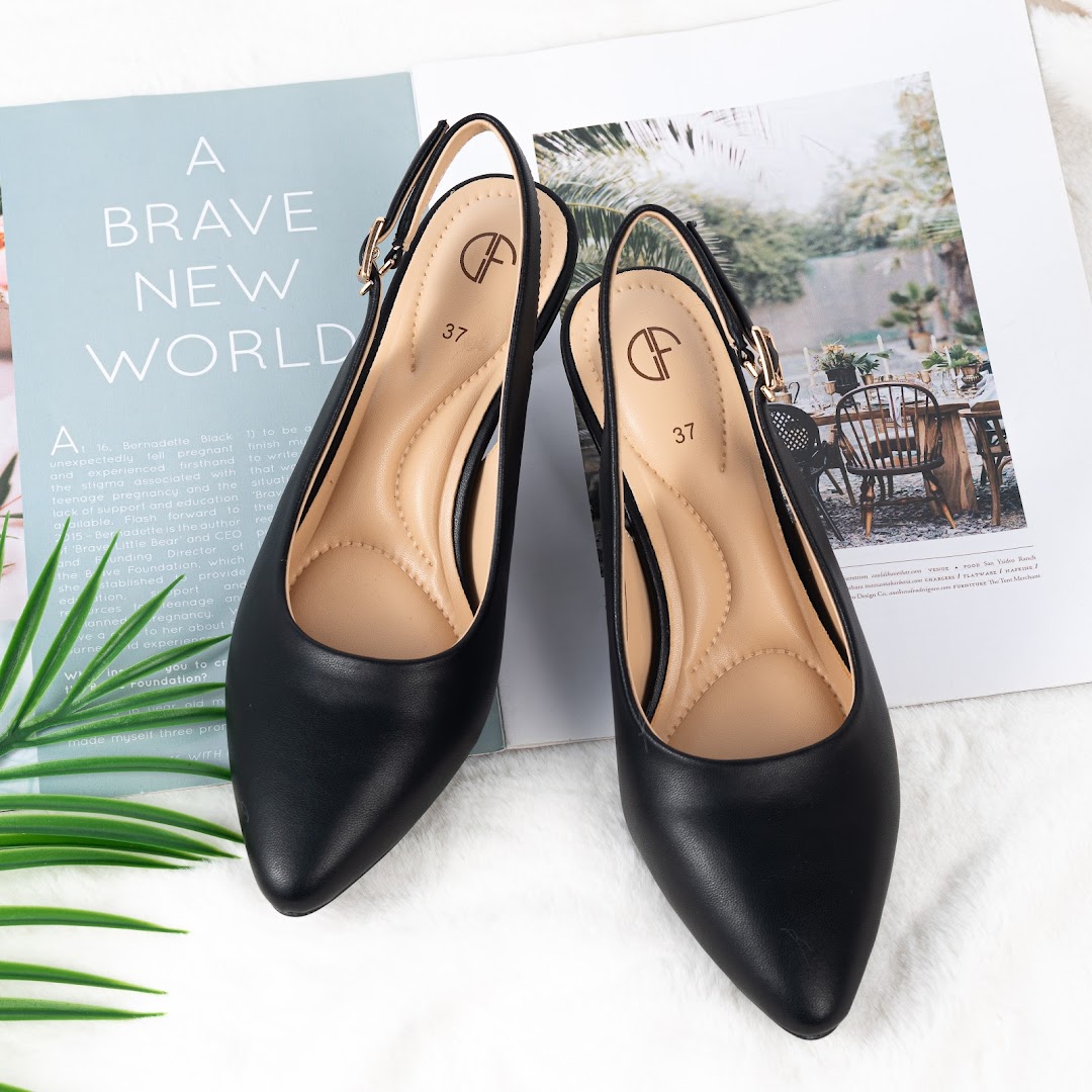 A pair of elegant black slingback shoes with pointed toes displayed on a magazine.