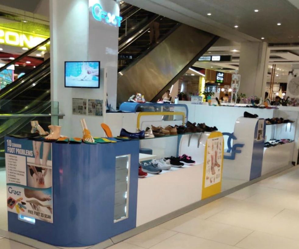 An interior view of the CFOOT kiosk in a mall, showcasing footwear, insoles, and foot health displays.