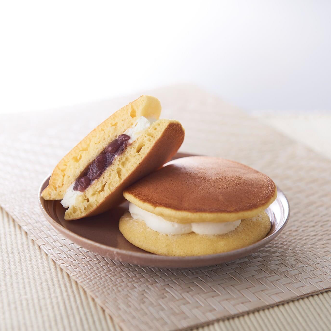 Two delicious dorayaki-style pancakes filled with sweet red bean paste and fresh cream on a plate.