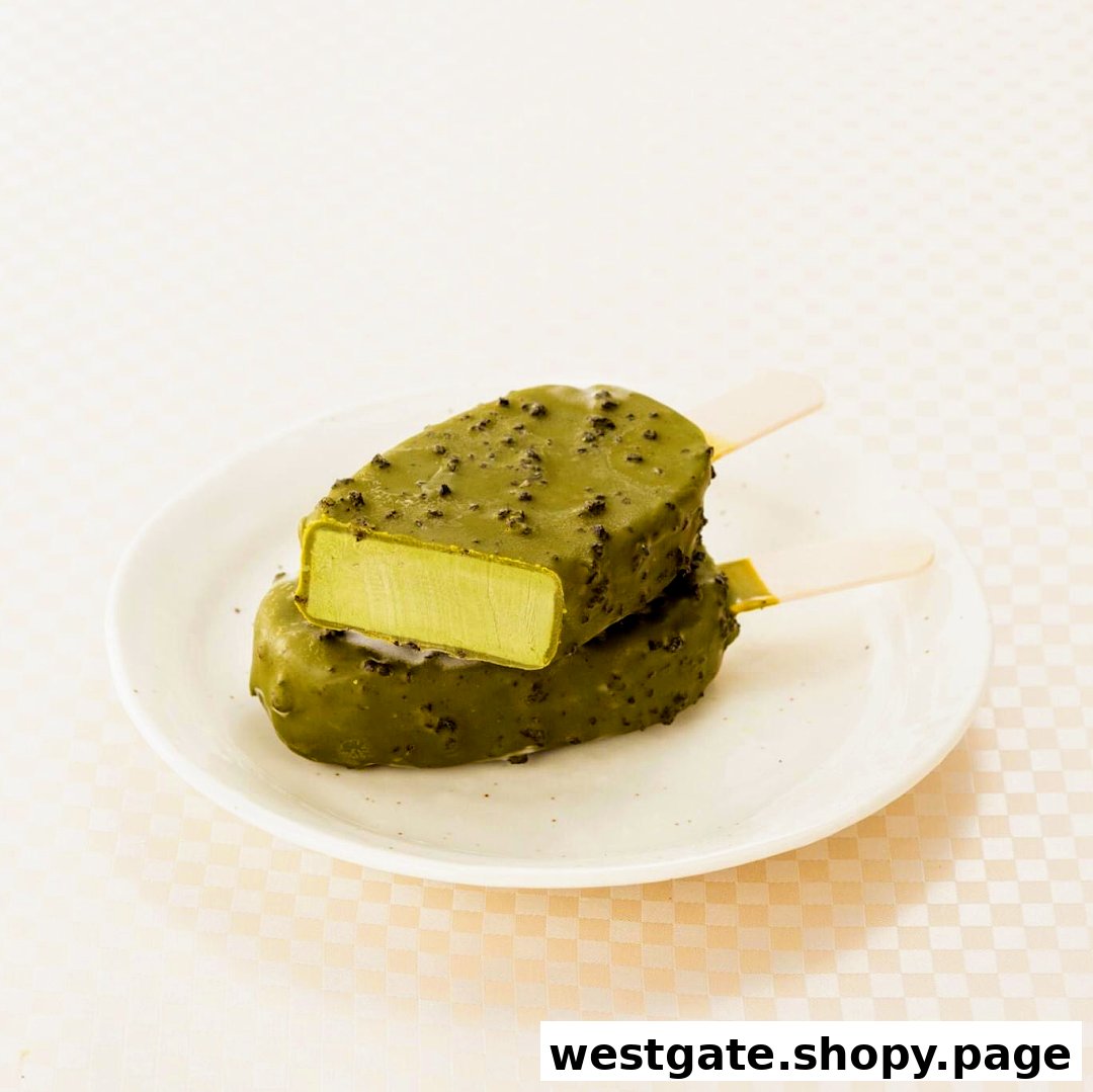 Two matcha ice cream bars, one cut open to reveal the green interior, are displayed on a white plate.