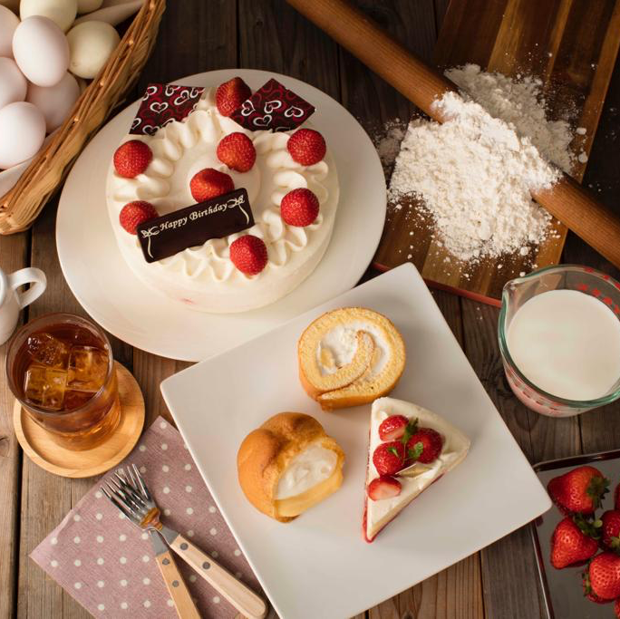 A delightful spread of Châteraisé desserts including a strawberry birthday cake, cream puff, and swiss roll.