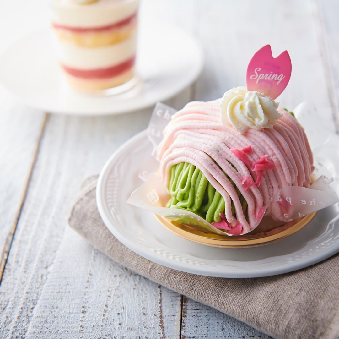 A beautifully crafted pink and green dessert, possibly a Mont Blanc, with a 'Spring' tag on a white plate.