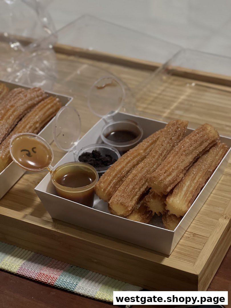 Two boxes of golden churros served with caramel, chocolate, and cookie crumb dips on a wooden tray.