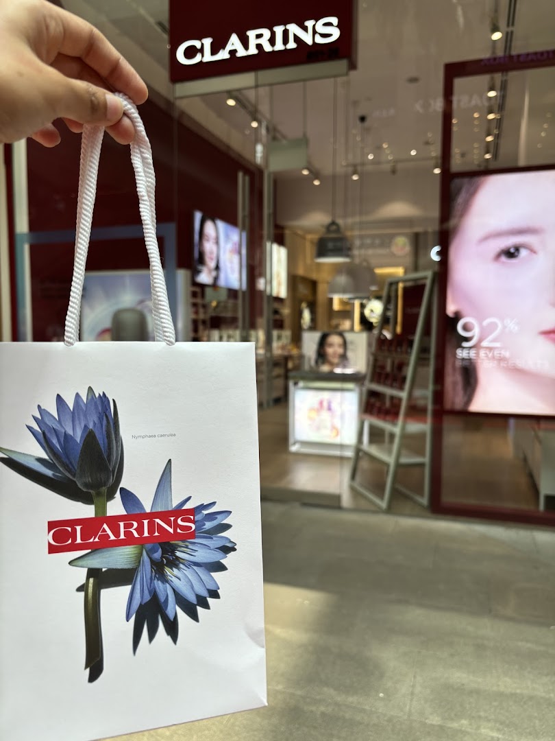 A hand holds a Clarins shopping bag in front of the Clarins boutique entrance at Westgate.