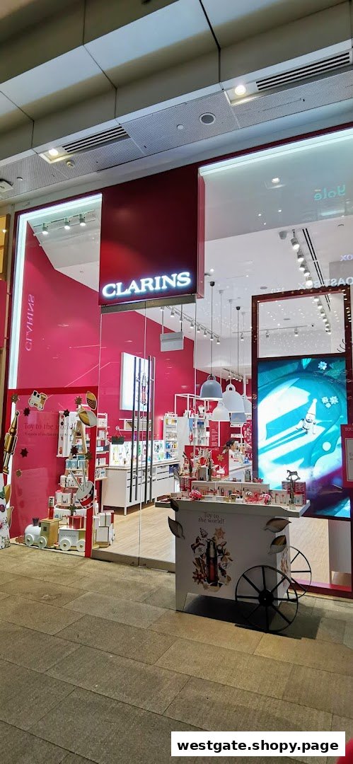 The Clarins boutique entrance features vibrant pink decor and festive holiday displays.