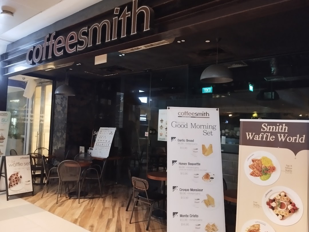 The exterior of Coffeesmith cafe, featuring its entrance, outdoor seating, and promotional banners.