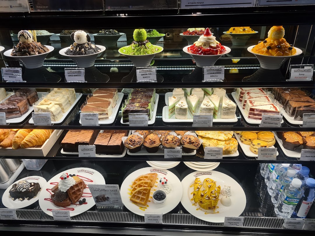 A vibrant display case showcasing a variety of delicious desserts, cakes, bingsoo, waffles, and pastries.