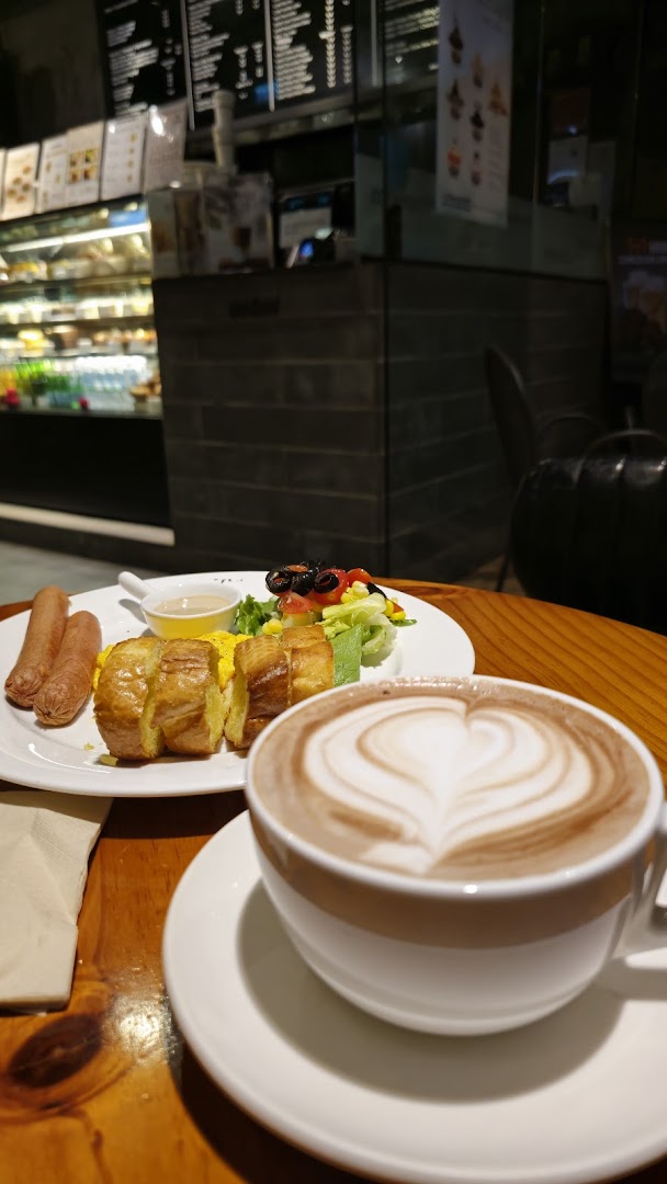 A cozy shot of a hot chocolate with latte art and a breakfast plate on a wooden table.