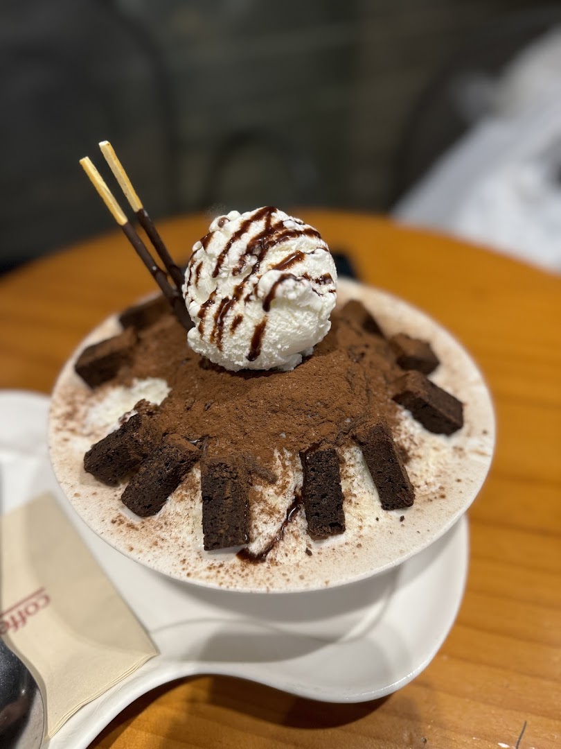 A delicious chocolate bingsu topped with vanilla ice cream, chocolate drizzle, and brownie pieces.