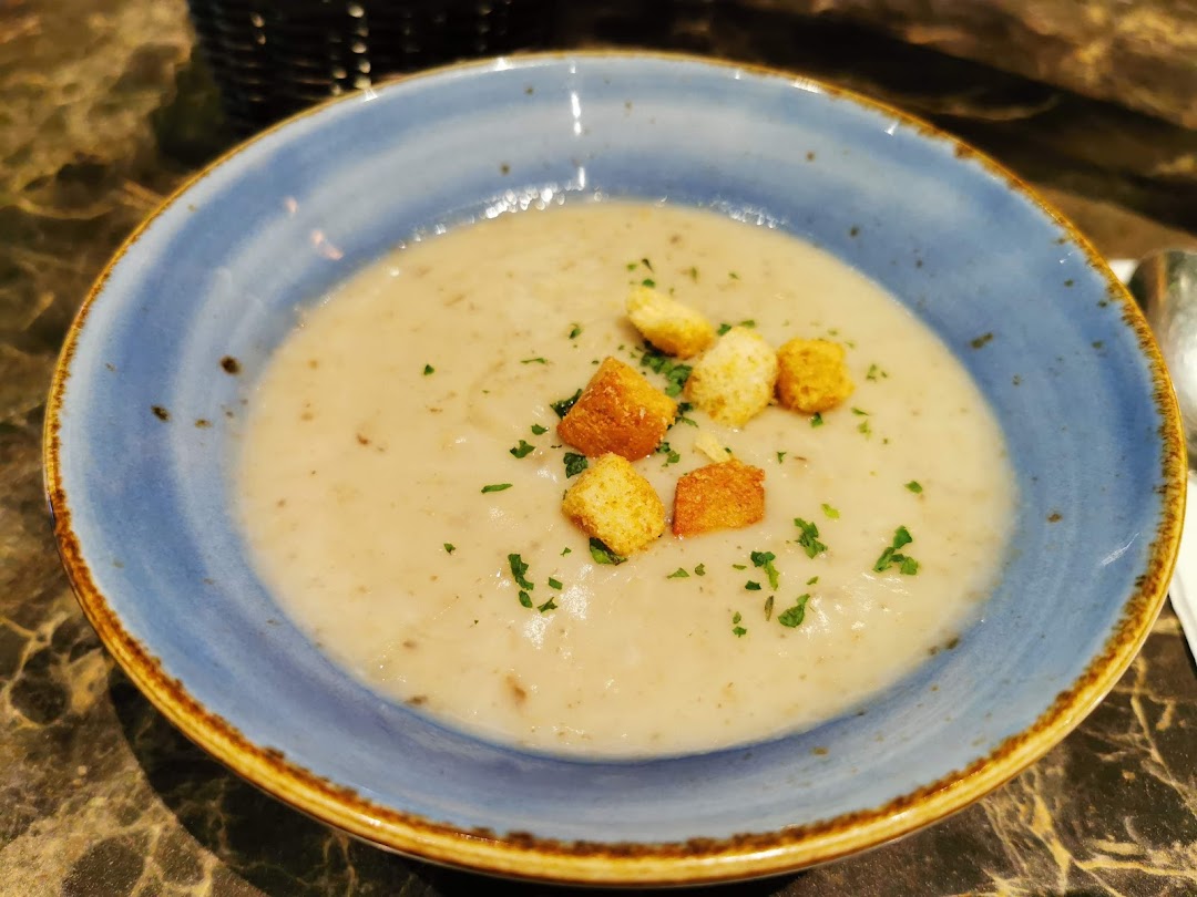 A close-up of a creamy mushroom soup with croutons and parsley in a blue bowl.