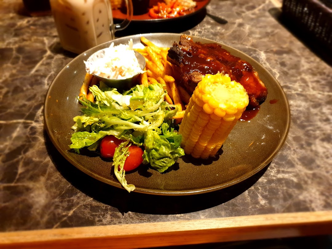 A plate of BBQ ribs, fries, salad, coleslaw, and corn on the cob.