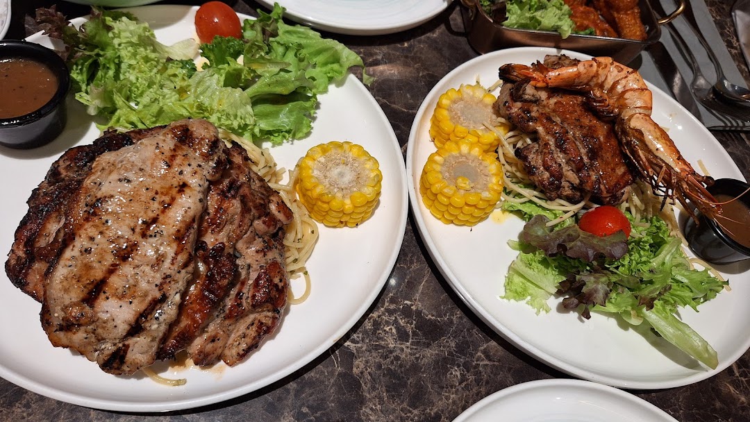 Two plates featuring grilled meats, seafood, pasta, corn, and fresh salads from COLLINS Westgate.