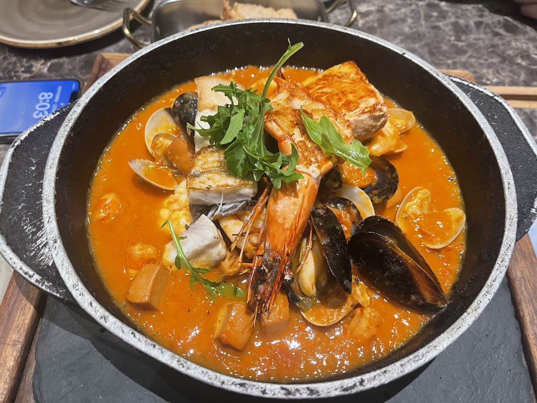 A vibrant seafood stew with prawns, mussels, clams, and fish in a rich tomato-based sauce.