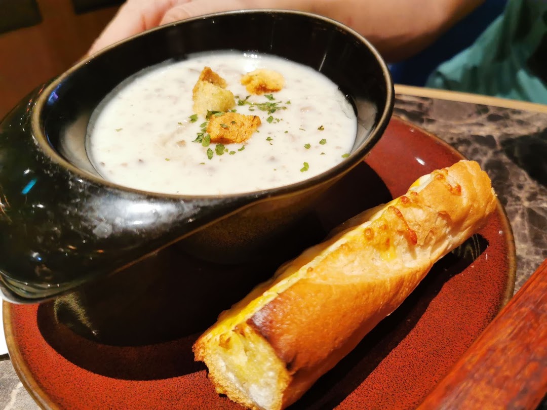 A creamy mushroom soup with croutons and a side of cheesy breadstick on a red plate.