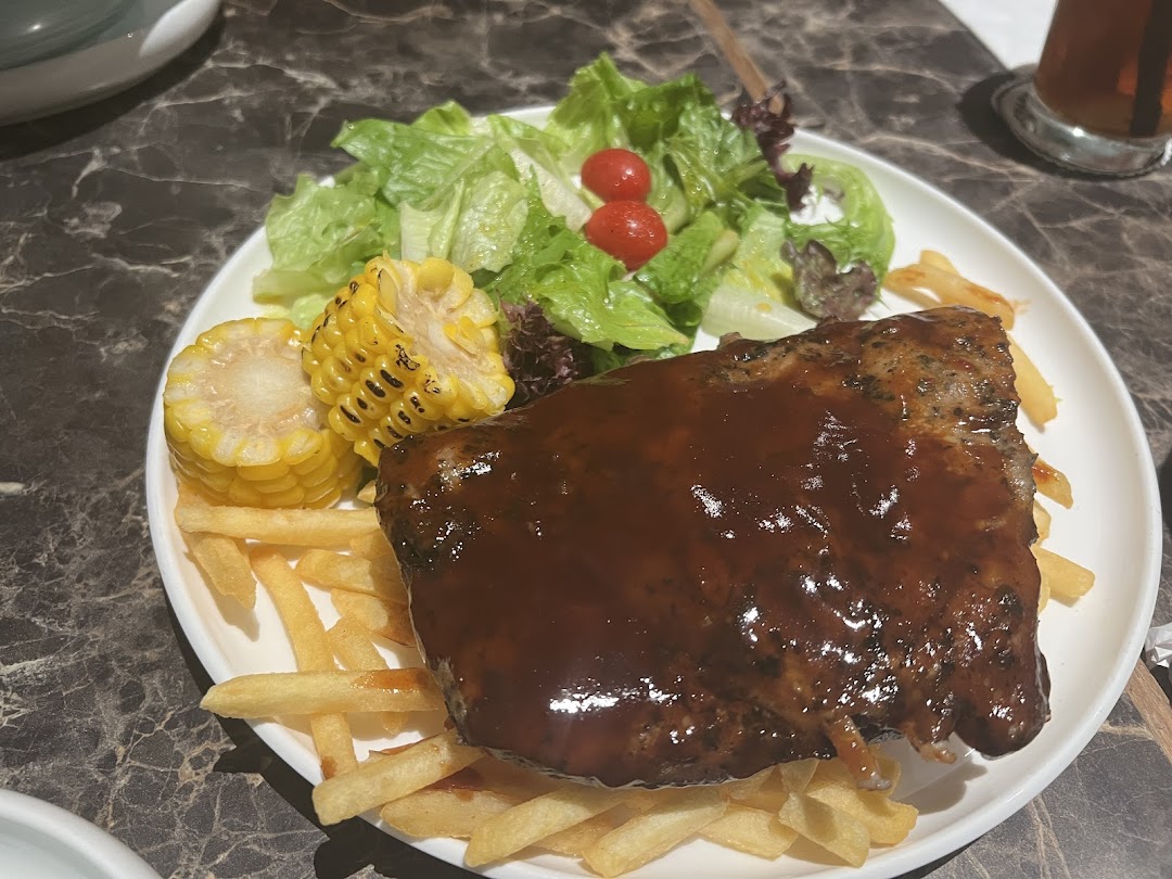 A plate of BBQ ribs with fries, corn on the cob, and a fresh side salad.