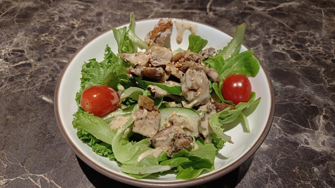 A vibrant salad featuring grilled chicken, fresh greens, cherry tomatoes, and a creamy dressing.