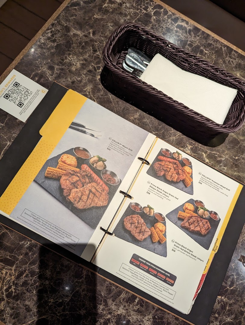 An open menu at COLLINS Westgate showcasing various grilled meats and steak options.