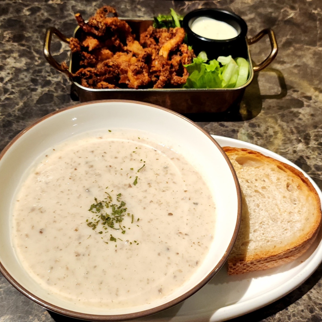 A creamy mushroom soup with bread and a tray of crispy fried calamari with dipping sauce.