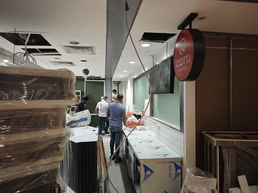 Workers are setting up the interior of a Cotti Coffee shop, with equipment and materials visible.