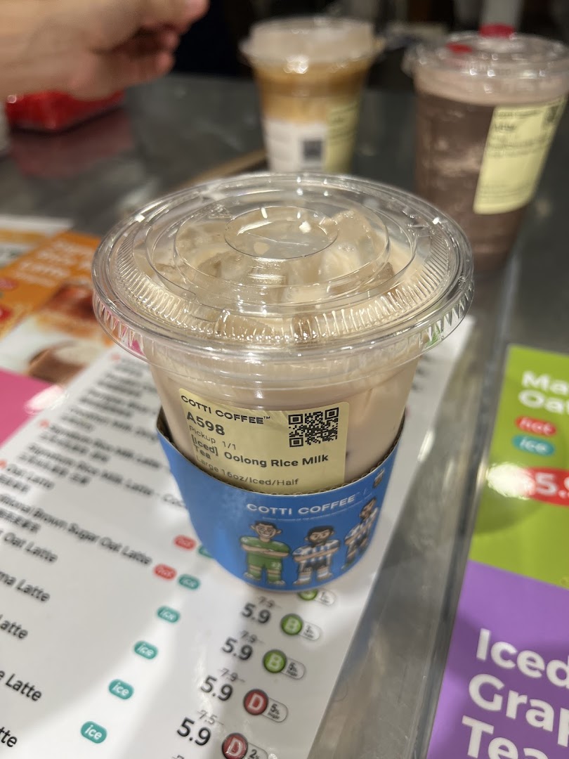 A refreshing Iced Oolong Rice Milk Tea from Cotti Coffee, with a partial menu visible in the background.