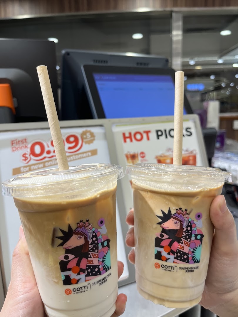 Two hands hold two iced coffee drinks from Cotti Coffee, featuring unique 'Suspensegirl' cup designs.