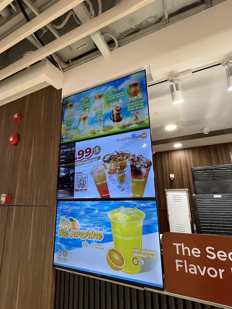 Digital menu boards at Cotti Coffee displaying various coffee and tea beverages, including promotional offers.