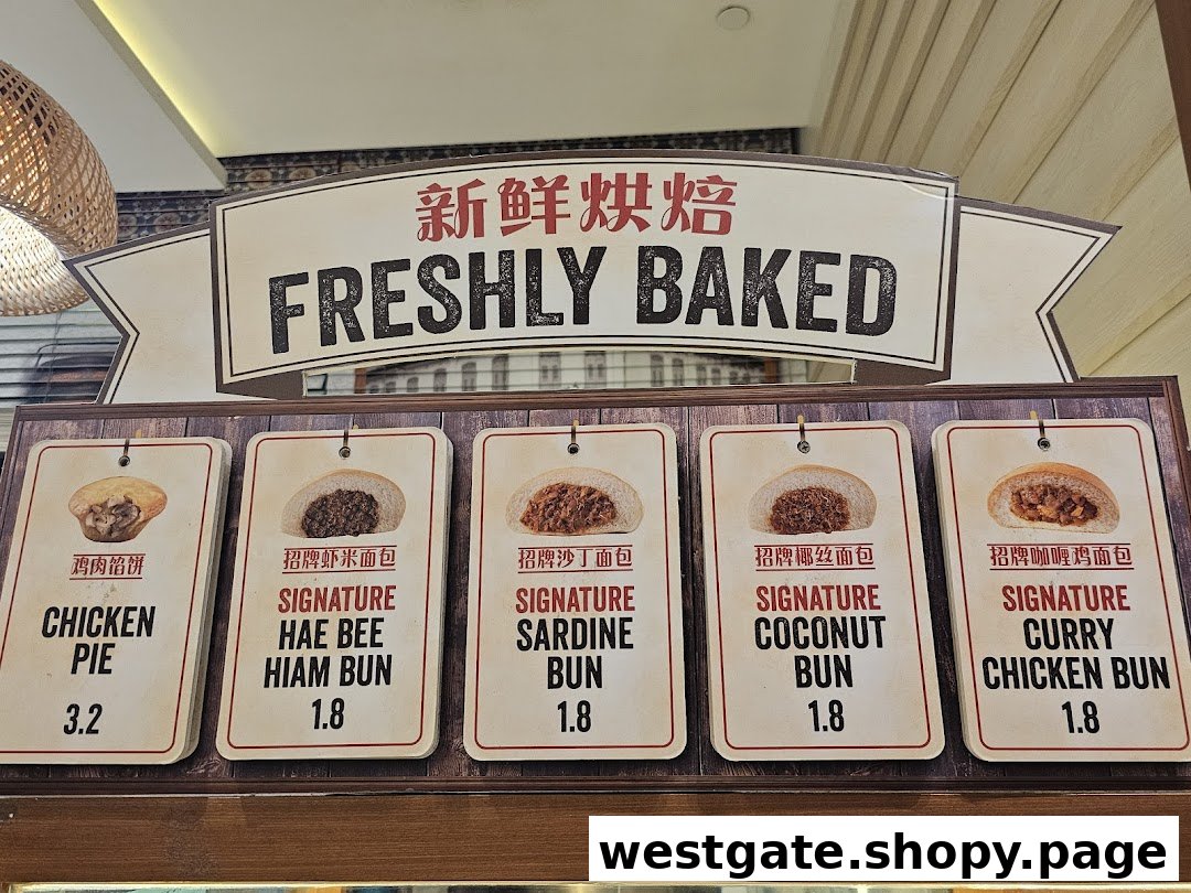 Display of freshly baked buns and a chicken pie with prices at Curry Times.